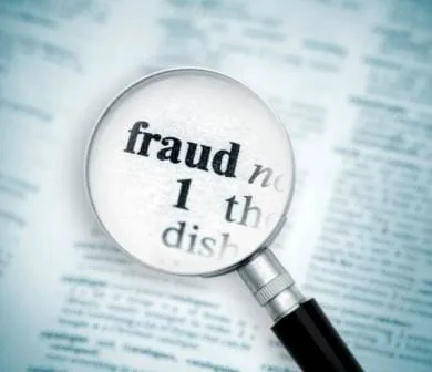 Person reviewing tax documents on a laptop while warning icons suggest scam alerts